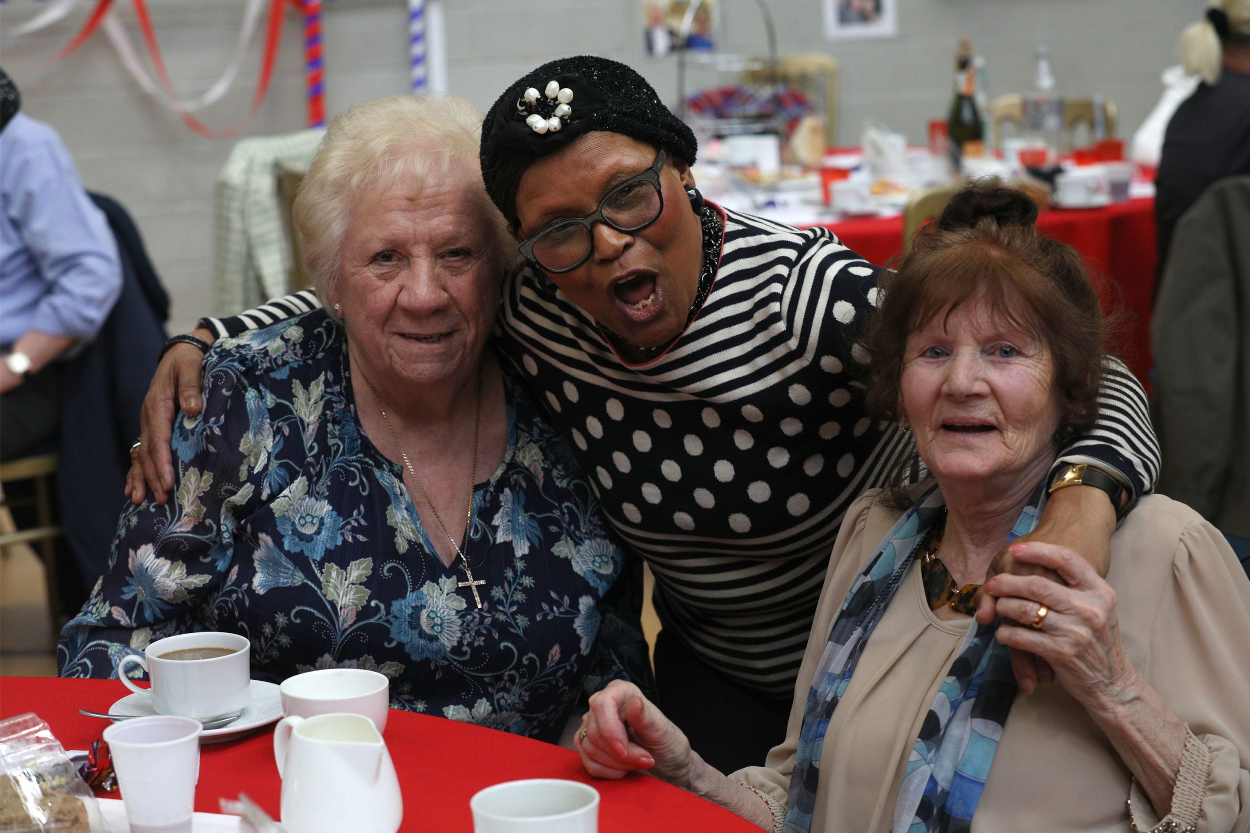 Three women drinking tea smiling at the camera